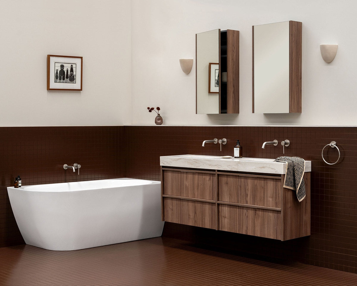Freestanding corner bath beside a walnut wall hung vanity with mirrored shaving cabinets