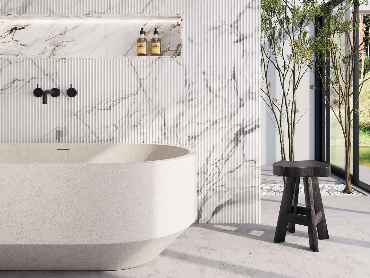 Terrazzo freestanding bath with a matte black wall mixer against marble look and fluted wall tiles