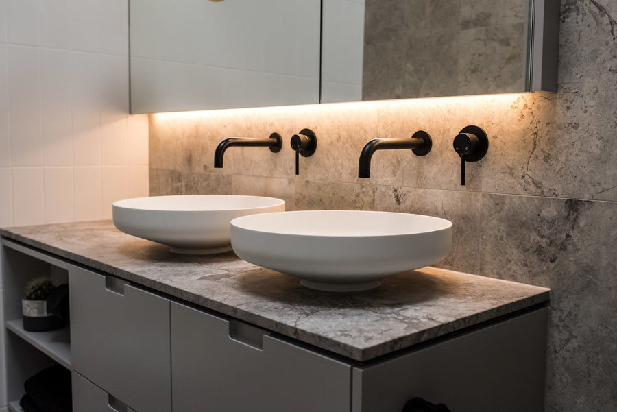 Twin round vessel basins with matte black wall mixers on a stone topped vanity