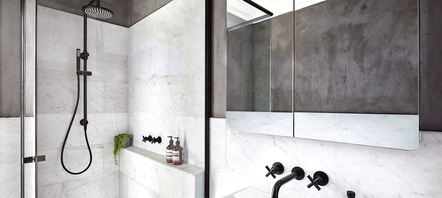 Matte black shower rail with a round overhead rose in a white marble look shower